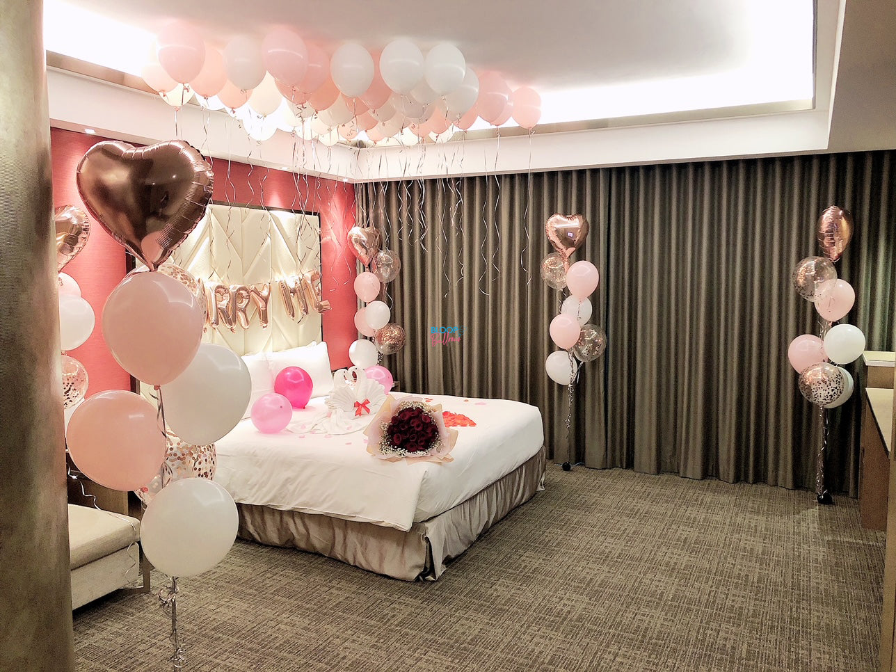 Luxury hotel room wedding proposal decorated with balloons, flowers and romantic styling