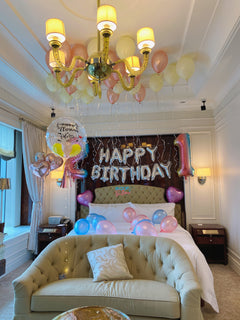 Decorated bedroom with balloons, a 'Happy Birthday' sign, and a chandelier.
