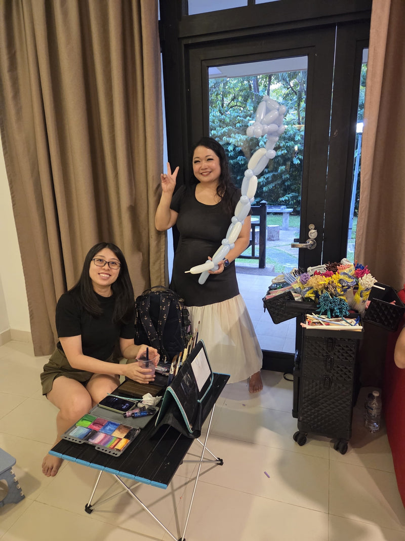 Balloon artist twisting a blue and white dragon balloon for children at a birthday party